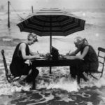 two women writing at a table on the beach
